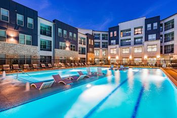 a swimming pool with chaise lounge chairs in front of a building
